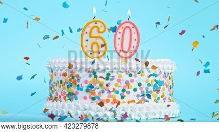 Colorful tasty birthday cake with candles shaped like the number 60.