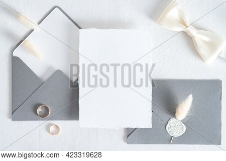 Wedding Invitation Card Template. Flatlay Blank Paper Card, Grey Envelopes, Goled Rings On White Bac