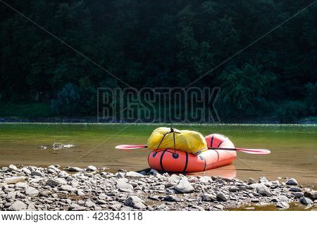 Orange packraft rubber boat with backpack on a river. Packrafting. Active lifestile concept