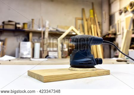 Electric Wood Sander On Wooden Table In Workshop. Woodworking Tool Concept. Furniture Metal Polisher