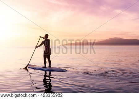 Adventurous Woman On A Paddle Board Is Paddeling In The Pacific West Coast Ocean. Sunset Sky Art Ren