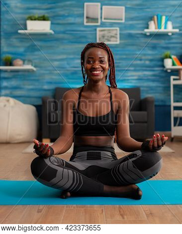 Portrait Of Black Woman Smiling Practicing Yoga At Home Sitting In Lotus Pose On Mat Mediting, Pract