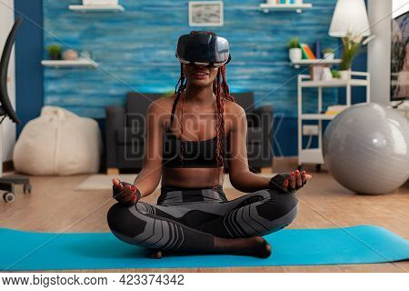 Black Woman Experiencing Virtual Reality Training Body And Mind Meditating In Lotus Pose Sitting On 