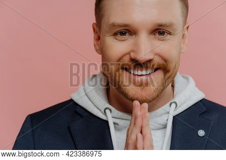 Close Up Portrait Of Cheerful Redhead Bearded Man In Casual Clothes Holding Hands In Praying Gesture