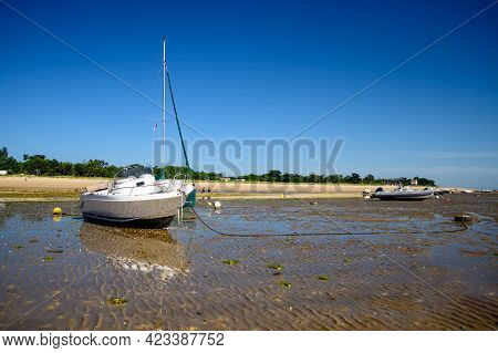 A Sailing Boat And A Motorboat Laying On The Beach Of Plage De La Loge At Portes-en-ré At Lowtide On