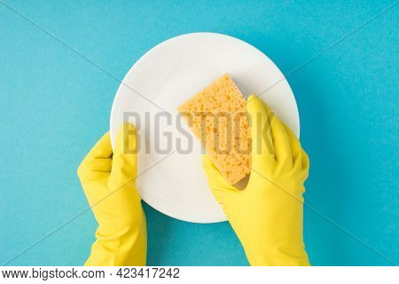 Top View Photo Of Hands In Yellow Rubber Gloves Holding Yellow Sponge And White Clean Dish On Isolat