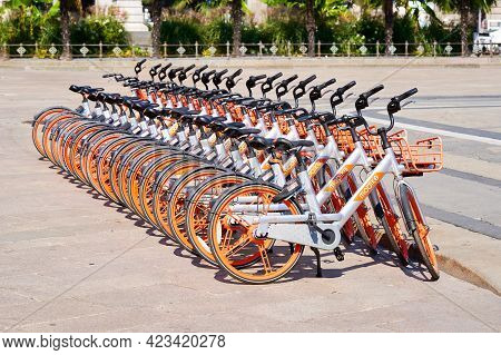 Bicycle Rental Service Mobike Stand In Row Parking On Duomo Square. Orange Bicycles With Basket For 
