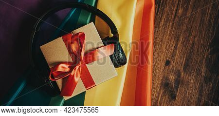 Gift Box With Red Bow Wireless Headphones For Christmas New Year On The Background Of The Rainbow Fl