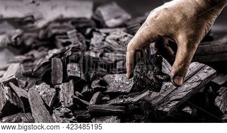 Hand Holding Piece Of Charcoal, With Background. Dirty Coal Emitter Hand
