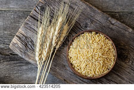 Raw Barley Noodle In Bowl On Wooden Background With Wheats, Uncooked Food Concept