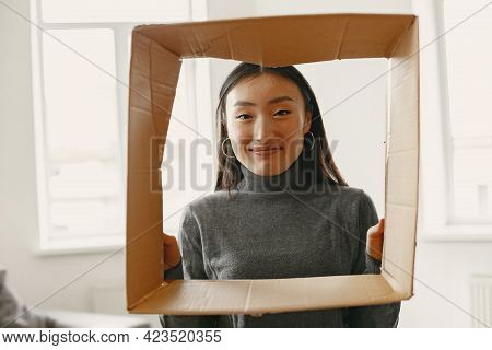 Asian Young Woman Looking Through Cardbox In New Flat