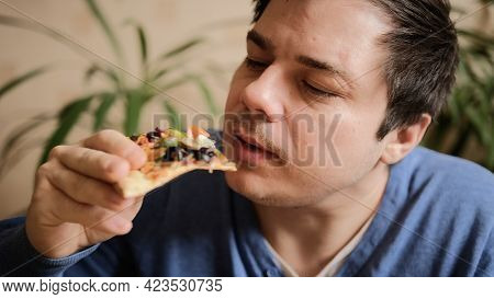 A Slightly Shaved Young Man Eats A Vegetarian Pizza With Mushrooms, Tomatoes, Peppers And Cheese. Th