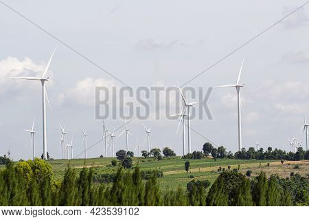 Rear View Man Engineer Wearing Personal Protective Equipment Working In Wind Turbine Farm Background