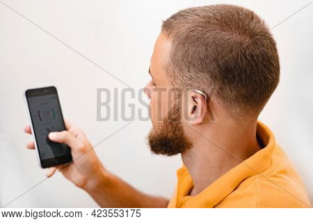 Hearing Impaired Man Adjusts Settings For His Bte Hearing Aid Via Smartphone. Hearing Aids, Deafness