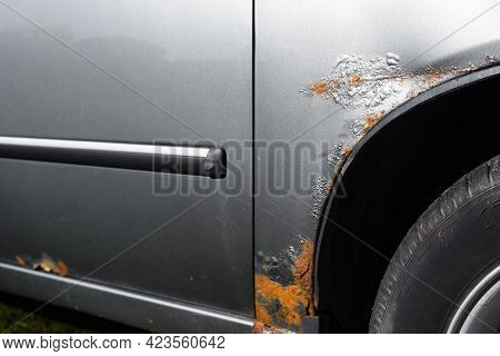 Damaged Car. Rust, Scratches And Cracked Gray Paint On The Front Fender Of The Car. Selective Focus 