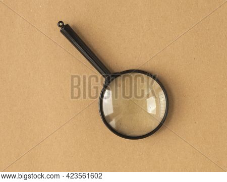 Magnifier Or Magnifying Lens Over Brown Carton Background. Search Tool.