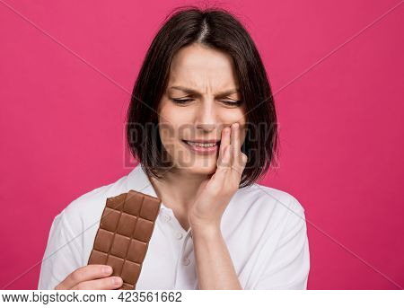 Beautiful Young Woman Bites A Bar Of Chocolate And Has A Toothache