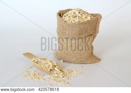 Oat Flake In A Sack And Spoon On The White Background. Heap Of Oats For Package Of Oatmeal Or Granol