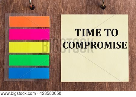 Text Time To Compromise On Yellow Note Paper On A Wooden Background Next To Colored Stickers. Busine
