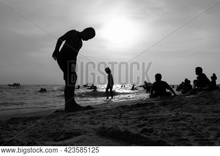 A Black And White Silhouette Of A Child Playing At The Sea In The Evening.