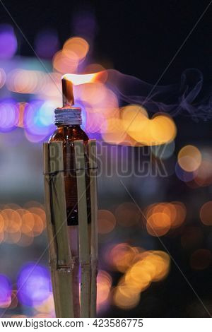 The Long Shot At The Top Of The Glass Bottle Is A Lit And Smoke Candle With A Bokeh Background.