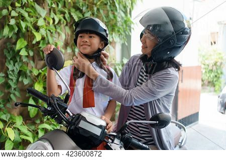 Mother Taking Her Daughter To School By Motorcycle In The Morning