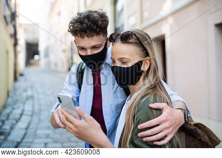 Young Couple Travelers Using Smartphone Sightseeing In City On Holiday, Coronavirus Concept.