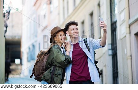 Young Couple Travelers With Smartphone Sightseeing In City On Holiday, Taking Selfie.