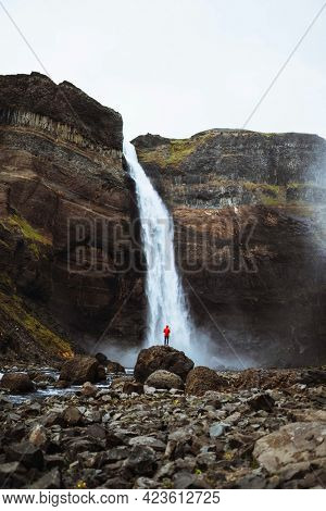 Man in a red jacket at the Haifoss waterfall, Iceland