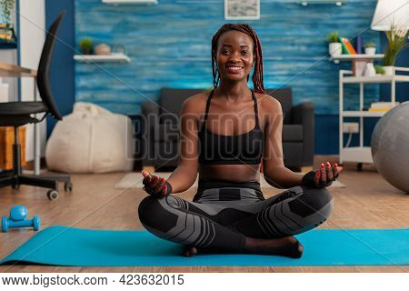 Fit Black Woman Practicing Yoga Sitting With Legs Crossed In Sportive Top And Leggins On Lotus Pose.