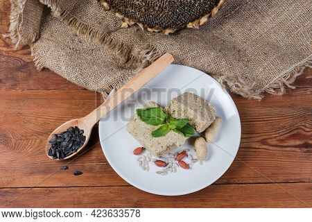 Sunflower Halva With Peanuts Addition And Whole Seeds On Dish On The Rustic Table With Dry Sunflower
