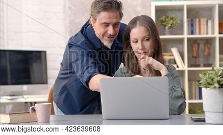 Business people working in office with laptop computer. Happy couple working from home at desk. Talking, meeting, cooperation, entrepreneurs, advisor.