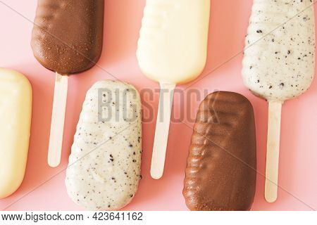 Line Of Milk And White Chocolate Popsicles On Light Pink Background, Top View