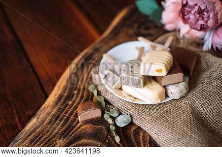 Still Life Of Chocolate Popsicle Lying On A Plate On A Wooden Table