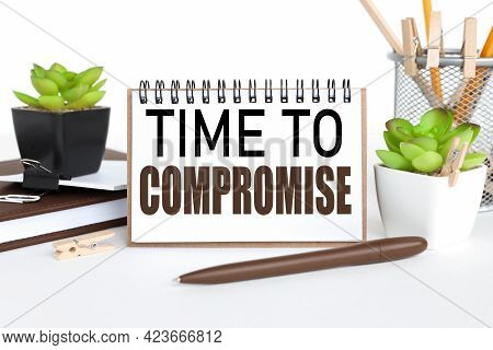 Time To Compromise. A Notebook On A Work Table, Near A Flowerpot And A Glass With Pencils