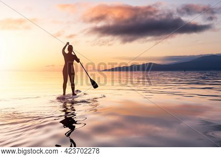 Adventurous Woman On A Paddle Board Is Paddeling In The Pacific West Coast Ocean. Sunset Sky Art Ren