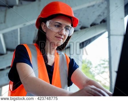 Construction Management. Woman Manager At A Construction Site. Woman In A Robot Builder Vest With A 