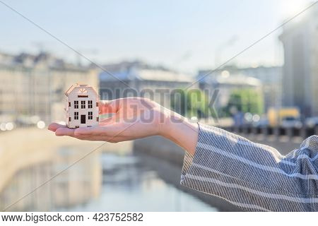 Small House On Hand Against The Background Of The City, Real Estate Agent Concept, Developers, Prefe