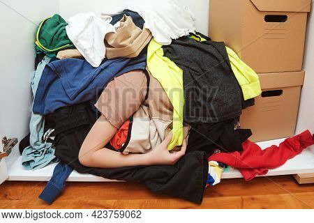 Lazy Boy Lying On The Thrown Clothes On The Floor. Mess In Open Wardrobe. Untidy Clutter Clothing Cl