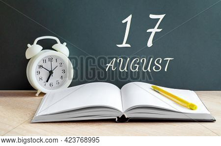 August 17. 17-th Day Of The Month, Calendar Date.a White Alarm Clock, An Open Notebook With Blank Pa