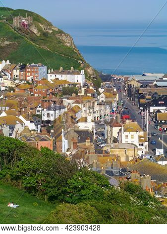 A View Of A Sunny Beach With A Town Line, A Few Beachgoers And A Calm Emerald Sea