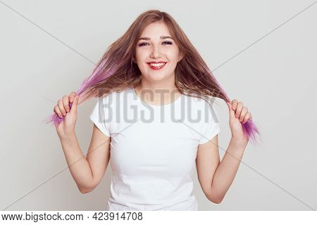 Portrait Of Smiling Happy Woman Of Young Age Looking At Camera With Toothy Smile, Pulling Her Hair A