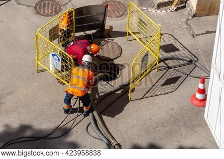 Saint Petersburg, Russia - June 08, 2021:workers Over An Open Sewer Manhole On The Street, Repairing