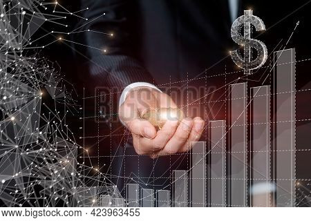 Business Man Shows A Handful Of Coins Against The Background Of A Growing Graph Of Financial Growth.