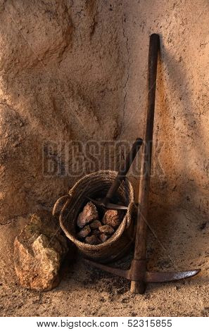 Ancient mining tools and basket full of rocks inside a tunnel in a mine