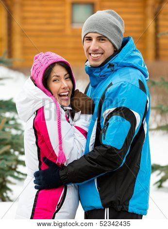Half-length portrait of hugging couple who wears warm caps and jackets during winter holidays