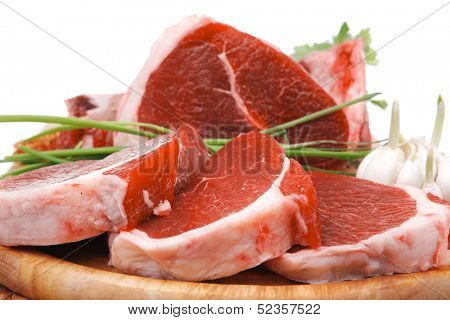 butchery : fresh raw beef lamb big rib and fillet ready to cooking with green stuff on wooden plate isolated over white background