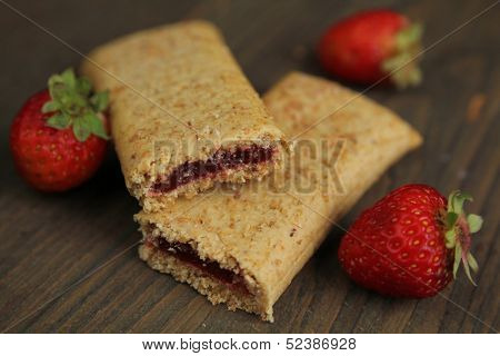 Organic cereal bar with fruit filling and fresh strawberry  on a wooden table