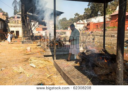 KATHMANDU, NEPAL - DEC 3, 2013: Unidentified local people during the cremation ceremony along the holy Bagmati River in Bhasmeshvar Ghat at Pashupatinath temple in Kathmandu.