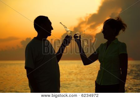 Mand og kvinde klirrer briller. Stænk af vin fra briller.